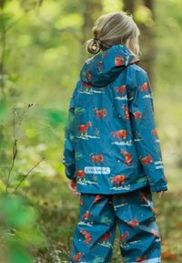 Vandtæt sæt med jakke og bukser til børn i blå, med et koskinds-mønster, justerbar hætte og elastiske manchetter. Fremstillet af slidstærkt materiale.