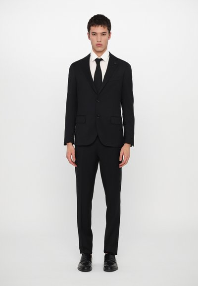 Costum negru cu un design slim fit, având două nasturi, rever în formă deățesă și buzunare laterale. Asortat cu o cămașă albă și o cravată neagră, cu finisaj mătăsos.