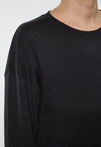 Czarny dzianinowy sweter z okrągłym dekoltem, długimi rękawami i gładką teksturą, prezentujący czysty, minimalistyczny design bez ozdobników.