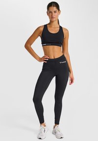 Sort sports-bh og leggings sæt, lavet af strækbart stof. Har et tætsiddende design, elastisk taljebånd og diskrete brandlogo detaljer.