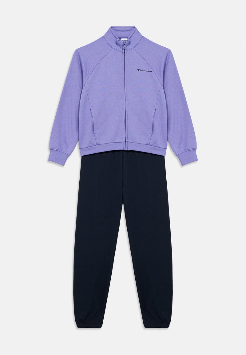 Μωβ ζακέτα με φερμουάρ και γιακά, σε συνδυασμό με μαύρο παντελόνι. Διαθέτει μανίκια ράγκλαν, ελαστικά μανσέτες και ένα μικρό λογότυπο στη ζακέτα.