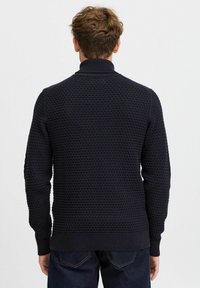 Maglione lavorato a maglia blu navy con un motivo testurizzato, colletto alto e polsini e orlo a costine. Realizzato in un tessuto morbido per il massimo comfort.