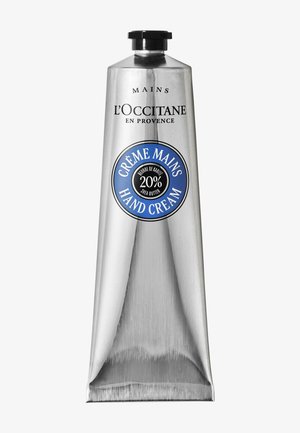 Zilveren tube handcrème van L'Occitane met 20% sheaboter, zwarte dop en blauw etiket op een effen witte achtergrond.