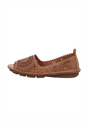 Tan cutout leather shoe featuring a rounded toe, scalloped edges, and a flat sole with raised dots for traction.