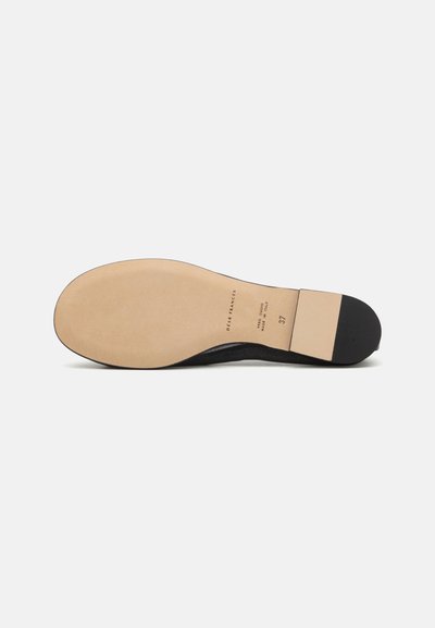 Semelle noire avec un intérieur beige lisse, dotée d'un talon plat et de détails de marque subtils. Forme arrondie avec un bord noir sécurisant.