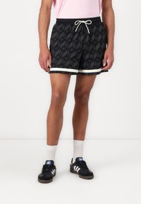 Black patterned shorts with a geometric design, elastic waistband, white drawstring, and contrasting white trim at the hem.