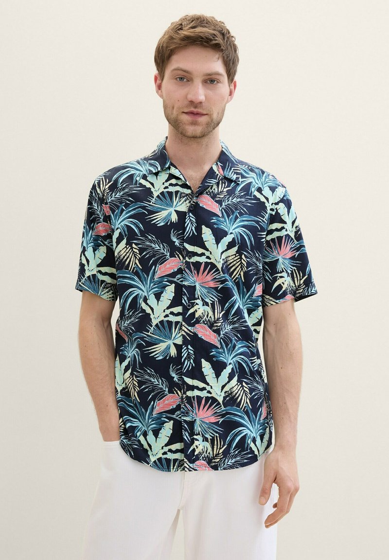 Camisa de manga corta con un fondo azul marino y patrones de hojas y flores tropicales multicolores. Tejido ligero, diseño de botones.