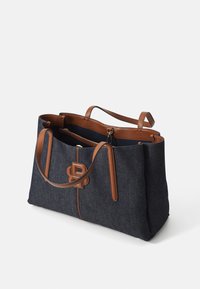 Denim-kassi ruskeilla nahkakoristeilla, jossa on kaksi kahvaa, vetoketjullinen sisätasku ja logo-edustus edessä.