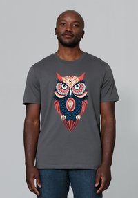 Grijze T-shirt met een gedetailleerde uilafbeelding in rood, blauw en crème, met complexe patronen en texturen op de veren van de uil.