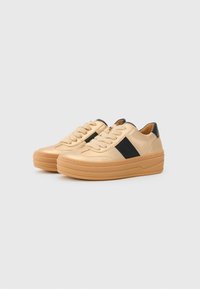 Sneaker beige con tomaia in pelle testurizzata, strisce laterali nere e spessa suola in gomma. Presenta lacci rotondi e dettagli impunturati.