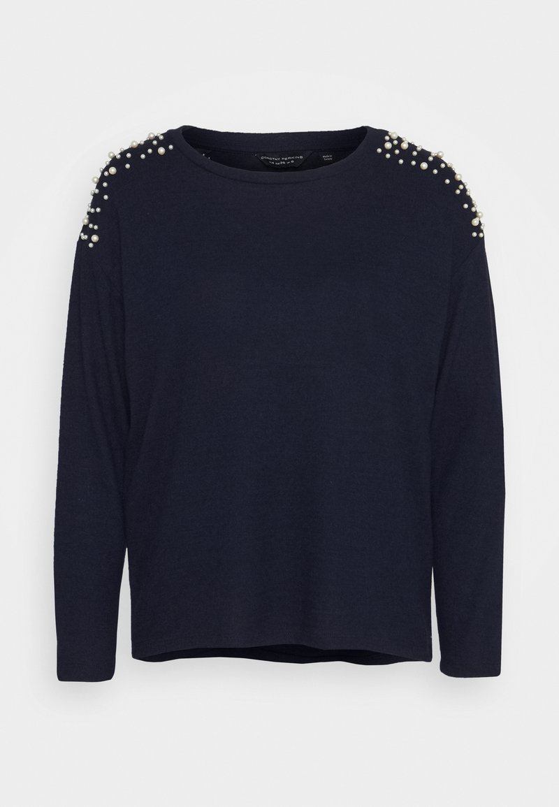 Granatowy sweter z długim rękawem o luźnym kroju, z perłowymi akcentami na ramionach i okrągłym dekoltem. Miękki materiał o delikatnej fakturze.