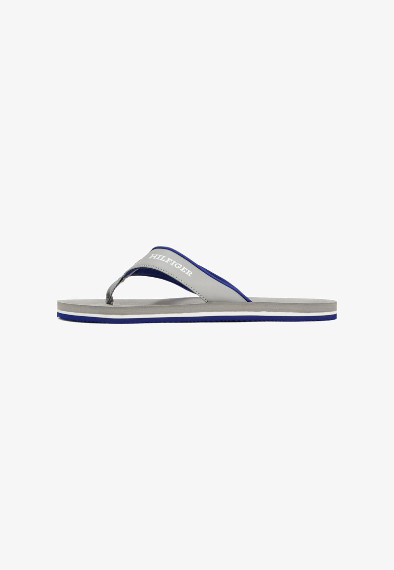 Grå flip-flop med blå accenter. Har en tekstureret tårem, flad sål og et hvidt logo. Enkel, minimalistisk design.