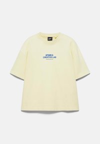 T-shirt à manches courtes couleur crème avec le texte bleu "STWD CREATIVE LAB" imprimé au centre devant.