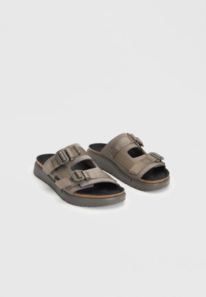 Paire de sandales marron à bout ouvert avec deux brides réglables à boucle et semelles intérieures rembourrées noires sur un fond clair uni.