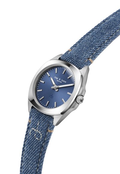 Quartz watch with a stainless steel case, blue dial, silver hour markers, and a blue denim strap featuring beige stitching and a logo.