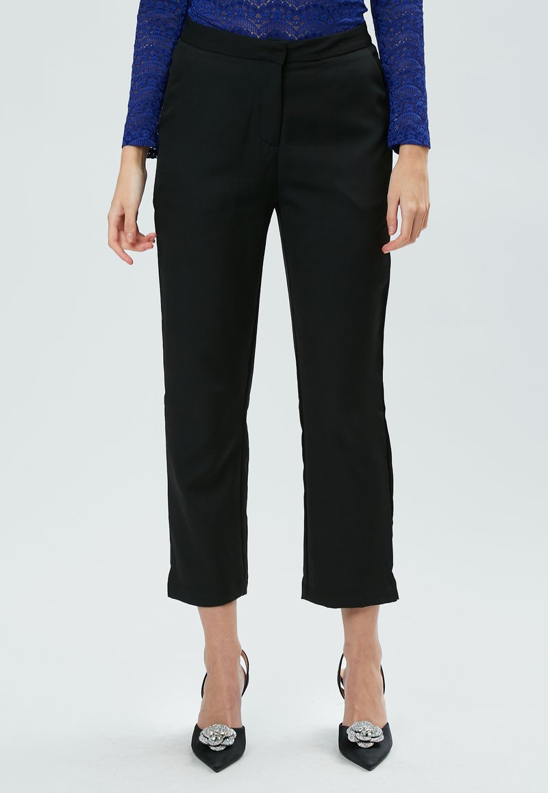 Zwarte cropped broek met een gladde textuur, met een getailleerde pasvorm en subtiele zijzakken. Geraadpleegd met zwarte hoge hakken en diamanten accenten.