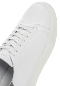 Baskets en cuir blanc avec bout arrondi, fermeture à lacets plate et semelle en caoutchouc texturée. Comprend des coutures discrètes et un design minimaliste.