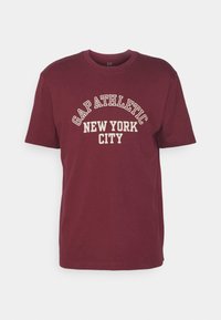 Camiseta de algodón burdeos con mangas cortas, que presenta el texto "GAP ATHLETIC NEW YORK CITY" en una impresión color crema, escote redondeado y corte estándar.