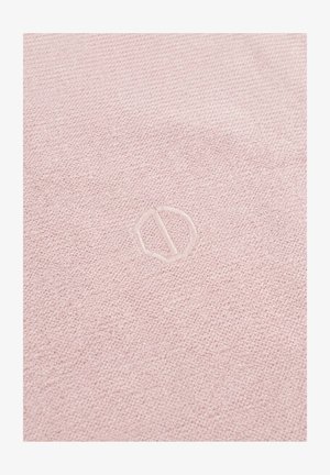 Lichtroze textiel met een subtiel, gegraveerd cirkelvormig logo met een diagonale lijn in het midden.