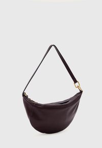 Vegan lederen tas in donker bordeauxrood. Ronde vorm met een enkele verstelbare riem en gouden hardware accenten. Gladde textuur en ritssluiting.