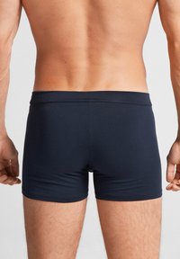 Boxers bleus marine en tissu stretch lisse, dotés d'une coupe ajustée et d'une taille subtile, mettant en avant un style minimaliste.