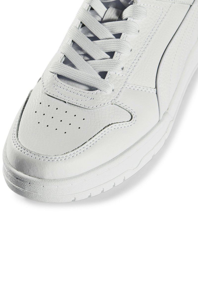 Białe sneakersy wykonane z teksturowanej skóry z perforacjami na palcach, z białymi sznurowadłami i gumową podeszwą z teksturowanym gripem.
