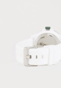 Λευκή σιλικόνη ζώνη ρολογιού με ατσάλινο κούμπωμα, με πράσινο κορώνα και λείο μεταλλικό πίσω μέρος. Διακοσμημένη με λεπτομέρεια branding.