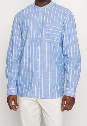 Chemise à manches longues bleu clair avec des rayures verticales blanches, un col montant, une poche frontale et une fermeture à boutons, fabriquée à partir d'un tissu texturé.