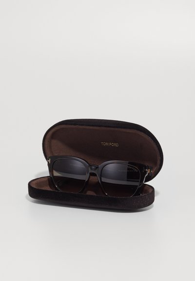 Tom Ford sunglasses in a rectangular shape, featuring dark lenses and a tortoiseshell frame, set in a black velvet case with gold branding.