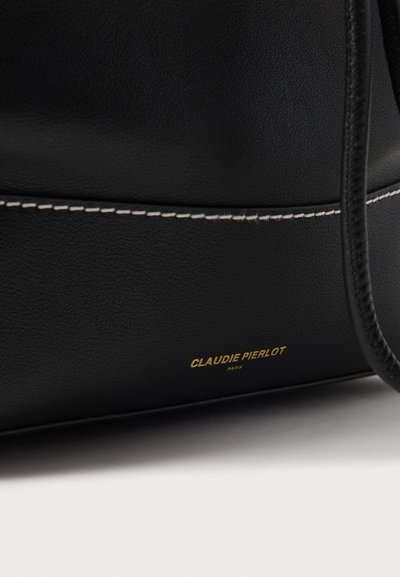 Sort læderhåndtaske med kontrasterende hvide syninger og en guldfarvet logo, med en glat tekstur og rund form.