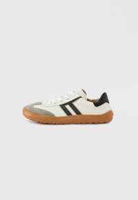 Chaussures de sport avec une tige en textile blanc et gris, des accents noirs et une semelle en caoutchouc marron. Elles disposent de lacets blancs et d'un motif rayé.