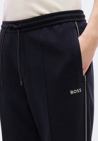 Μπλε ναυτικού χρώματος παντελόνια jogging από υφή υφάσματος με ελαστική μέση, κορδόνι και πλαϊνές τσέπες. Διαθέτει διακριτική επωνυμία "BOSS" με ανοιχτόχρωμα γράμματα.