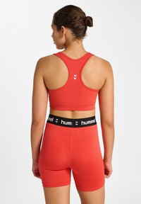 Rotes sportliches Sport-BH- und Shorts-Set aus dehnbarem Stoff. Verfügt über einen schwarzen, gebrandeten Taillenbund und ein Logodesign auf der Rückseite.