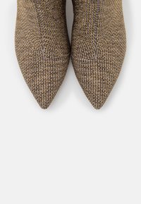 Pointed-toe shoes made of textured brown and gold woven fabric, featuring a structured design for a sleek appearance.