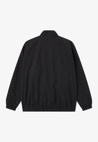 Veste noire avec un motif répétitif, col haut, manches et ourlet élastiques, présentant une texture lisse et un matériau léger.