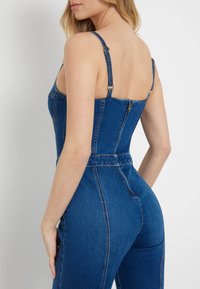 Denim šokinys su prigludusia korsetinio stiliaus dalimi, be nugaros, plonais reguliuojamais petnešomis ir auksiniu užtrauktuku. Medžiaga yra lygi ir elastinga.