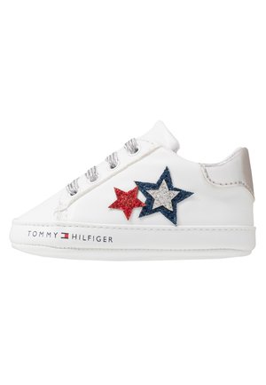 Baskets basses blanches avec lacets argentés, étoiles rouges et bleues scintillantes sur le côté, et logo Tommy Hilfiger sur la semelle blanche.