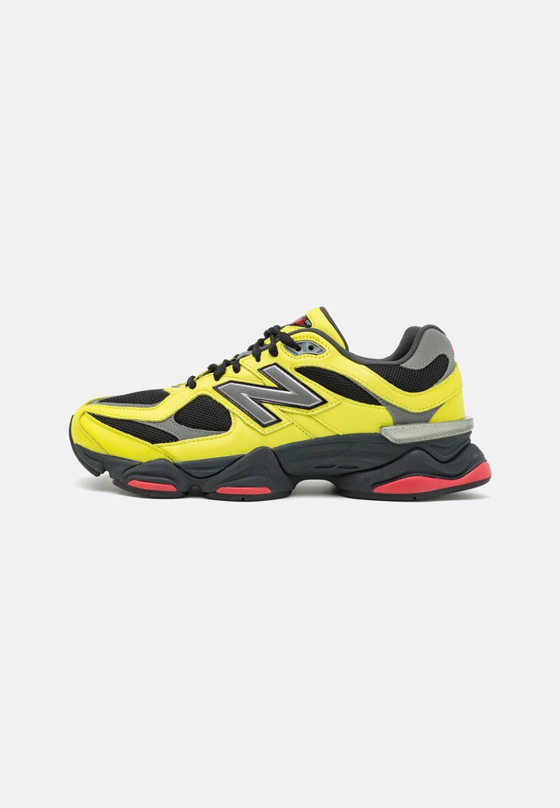 Black and yellow sneaker with mesh upper, rubber sole, and gray accents. Features reflective details and a structured shape.