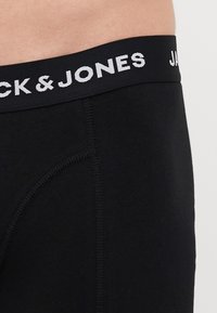 Schwarze Baumwollunterwäsche mit einem weichen Bund, auf dem "Jack & Jones" in Weiß gestickt ist. Glatte Textur und figurbetontes Design ohne Muster.