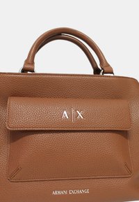Borsa a tracolla in pelle marrone con texture, dotata di tasca a pattina, logo iniziali "A|X" in argento e doppi manici superiori. Design minimalista con accenti sottili.