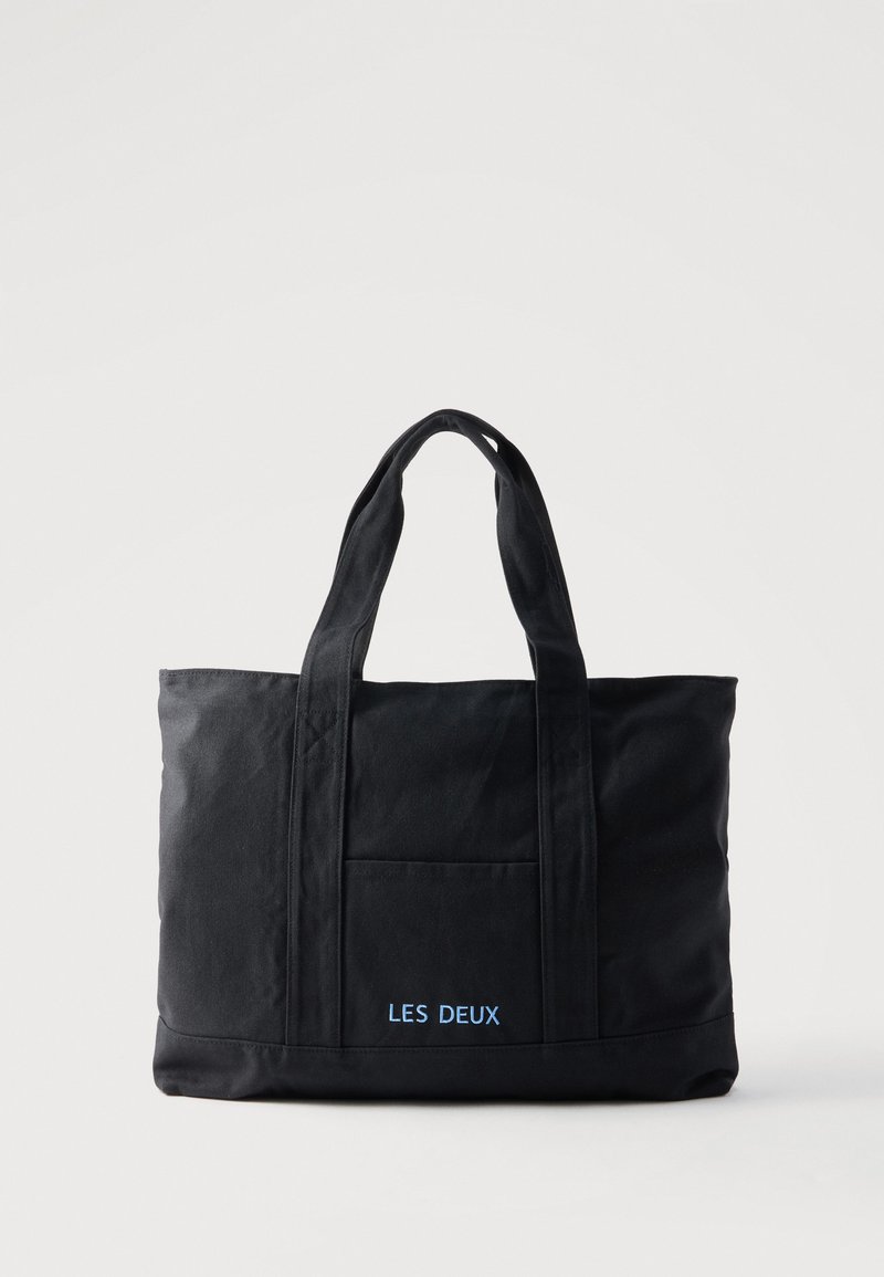 Sac cabas en toile noire avec deux anses, poche avant et "LES DEUX" brodé en bleu sur la poche avant.