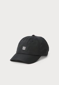 Black baseball cap made of fabric, featuring a curved brim and “HUGO” logo in white. Textured surface with stitched accents and eyelets.