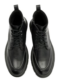 Czarne skórzane botki za kostkę o fakturowanym wykończeniu, okrągłym nosku i płaskiej gumowej podeszwie. Posiadają sznurowanie z przodu oraz pętlę do łatwego zakładania.