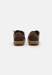 Braune Leder- und Wildlederschuhe mit niedrigem Profil, weißer Zwischensohle und strukturiertem Gummisohle; mit Ziehschlaufen an der Ferse.