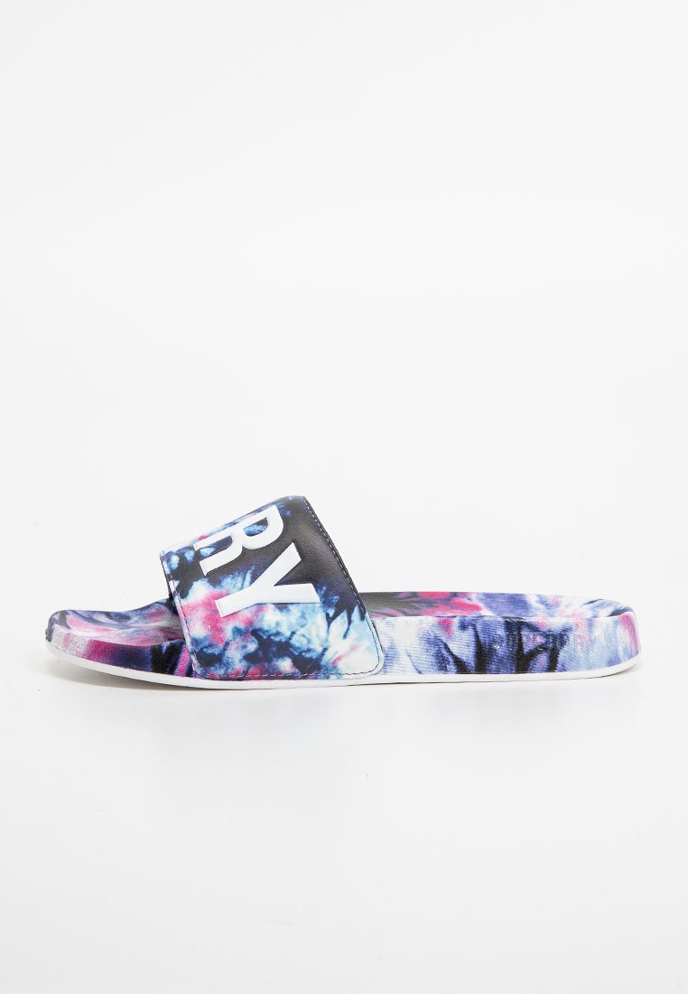 Schwarze und farbenfrohe Slidesandale mit einem breiten Riemen, der weißen Text aufweist. Strukturierte Oberfläche mit einem lebhaften blau-lila Batikmuster. Weiße Sohle.