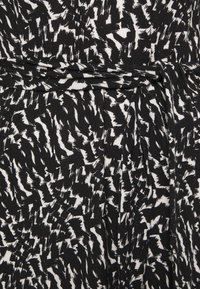 Tissu à motif abstrait noir et blanc avec un détail de ceinture nouée autour de la taille.