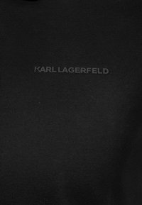 Czarna koszulka z krótkim rękawem z bawełny, z wypukłym czarnym logo "KARL LAGERFELD" z przodu. Gładka tekstura, dopasowany krój.