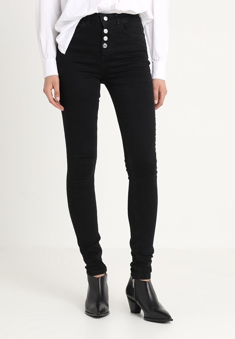Černé pružné džíny s vysokým pasem a pěti knoflíky, vyrobené z denimu. Hladká textura, obepínající design a délka ke kotníkům.