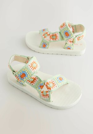 Sandale albe cu talpă texturată și curele din croșetat floral multicolor în verde, portocaliu și albastru.