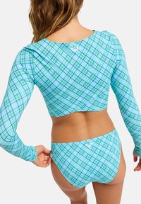 Μπικίνι δύο τεμαχίων με μακριά μανίκια και σλιπ ψηλής μέσης. Κατασκευασμένο από ύφασμα με καρό μοτίβο σε μπλε και πράσινους τόνους με διακριτικά λογότυπα.